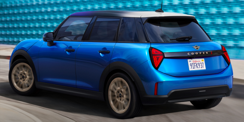 Blue 2025 MINI Cooper 4-Door Hardtop parked beside a blue brick wall, showing sleek design and shiny wheels.