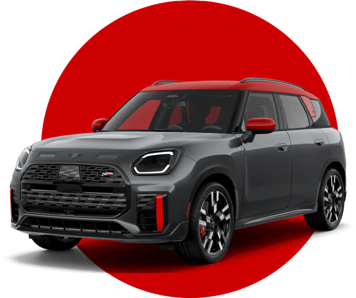 An angled view of a 2025 JCW Countryman ALL4 in front of a red circle against a black backdrop.