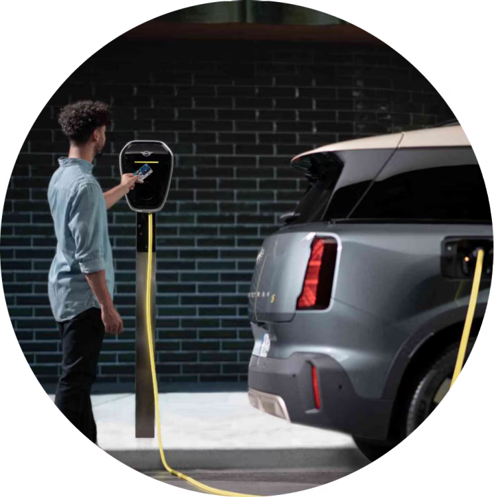 Side-view of a person charging their MINI Countryman SE ALL4 against a brick wall.