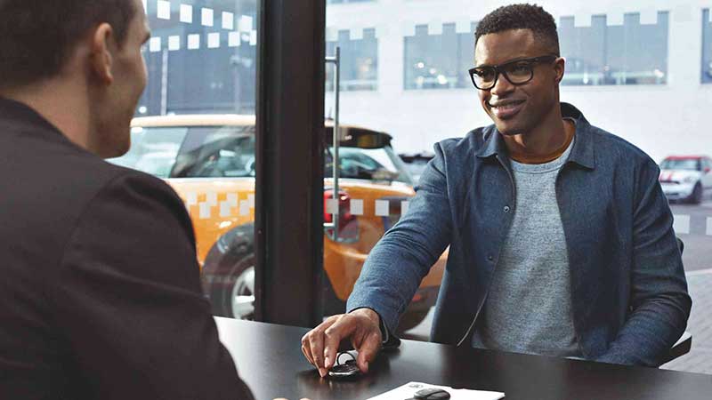 A man smiles while conversating at a MINI Dealership.
