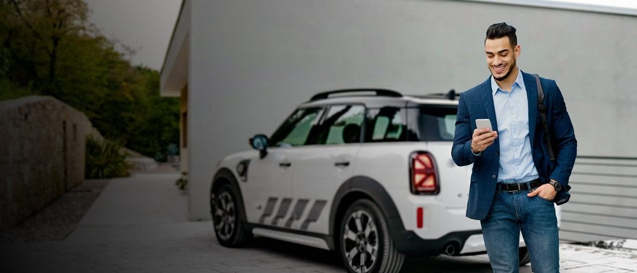 A man walks away from his parked MINI while on the phone