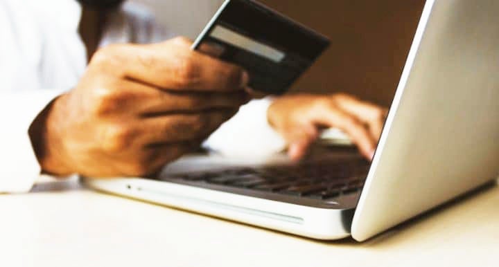 Hand holding credit card in front of open compute | MINI of Morristown in Morristown NJ